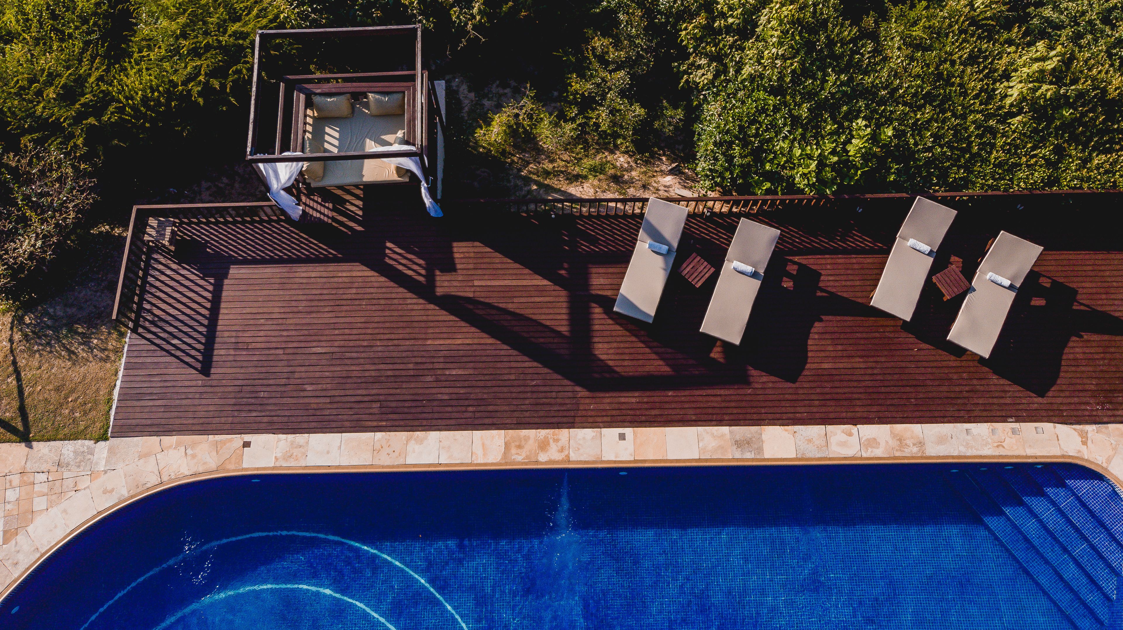 A rooftop pool area with a wooden deck, lounge chairs, and a diving board.
