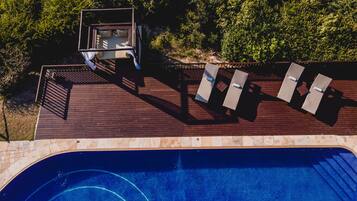 A rooftop pool area with a wooden deck, lounge chairs, and a diving board.