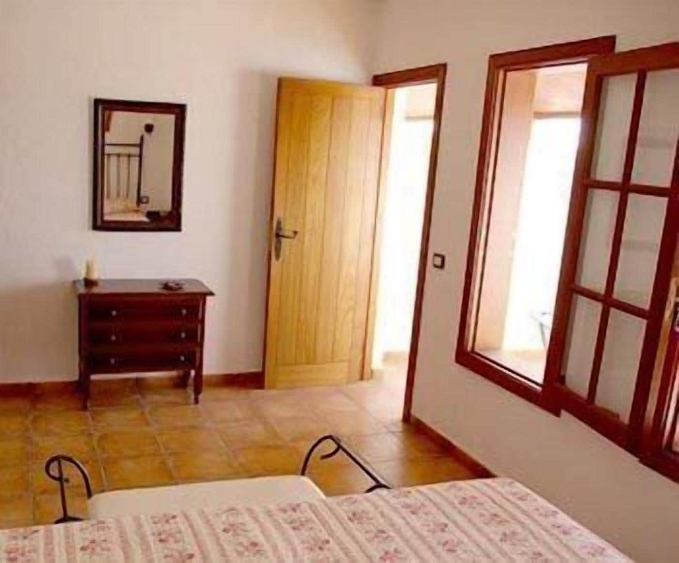 A bedroom with a bed, a dresser, a mirror, and a door leading to another room.