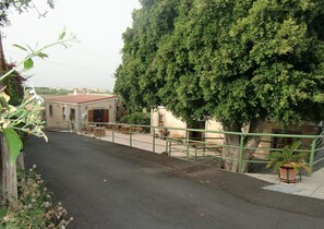 A courtyard with a building, a large tree, and outdoor seating. - Hotel Rural El Navío- Adults Only (Guia de Isora)