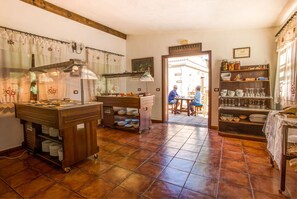 A kitchen with a large stove, a sink, and a counter with various kitchen items. There is a door leading to a dining area with a table and chairs. - Hotel Rural El Navío- Adults Only (Guia de Isora)