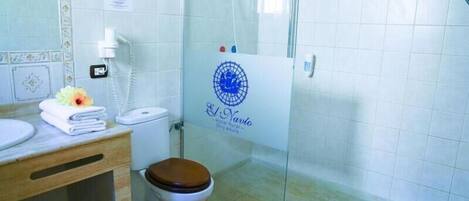 Een badkamer met toilet, wastafel, douche en een glazen deur met een logo.