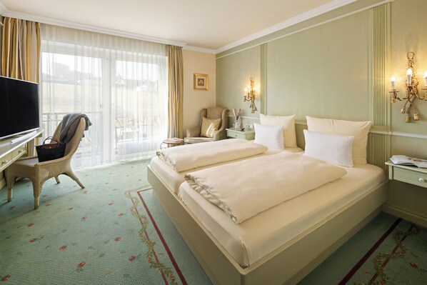 Une chambre d’hôtel avec un grand lit, un bureau avec une télévision, une chaise, une table de chevet et une fenêtre avec des rideaux.