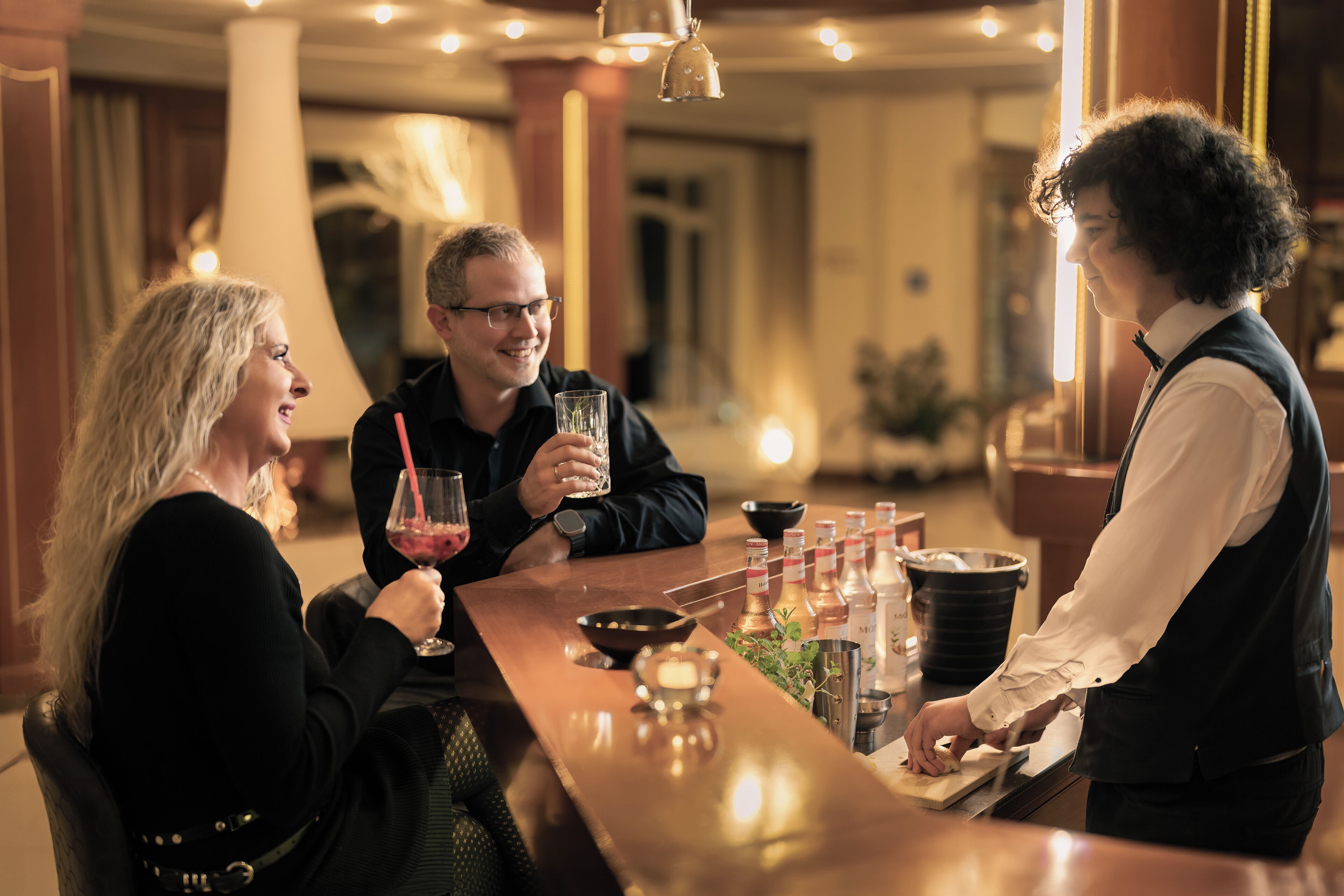 Zona de bar con un cantinero, una mujer y un hombre.