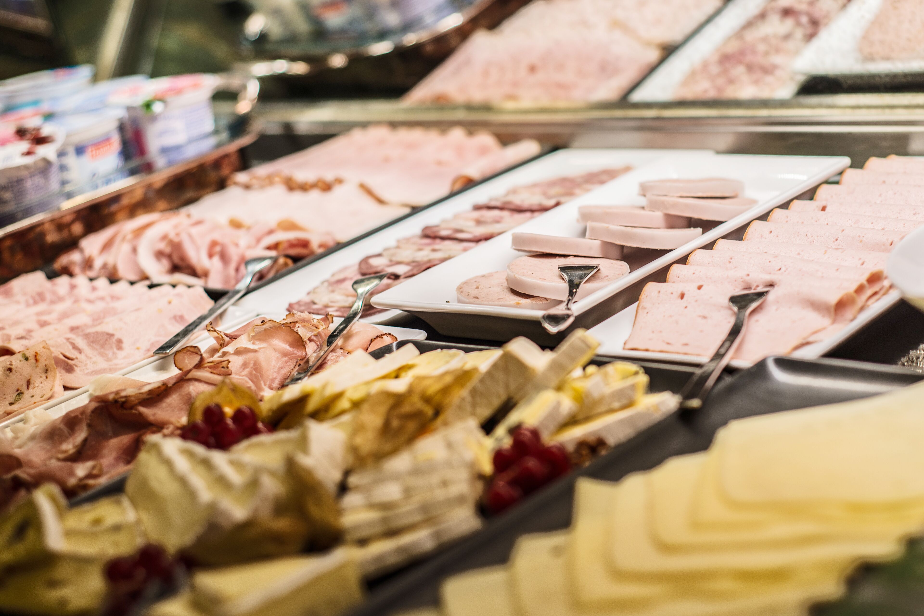 Un'ampia selezione di formaggi e salumi esposta in una vetrina.