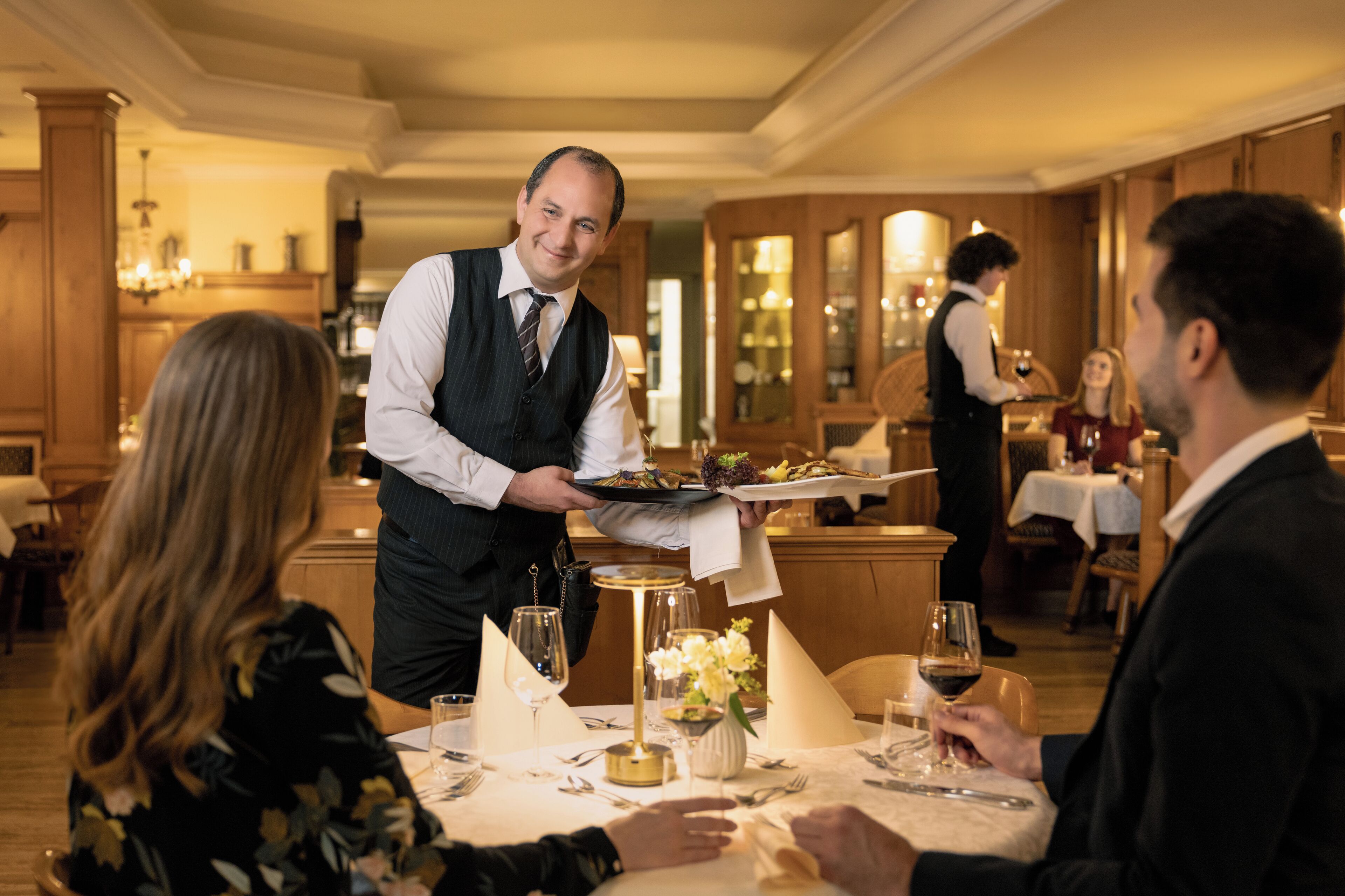 A formal dining setting with a waiter serving a meal.