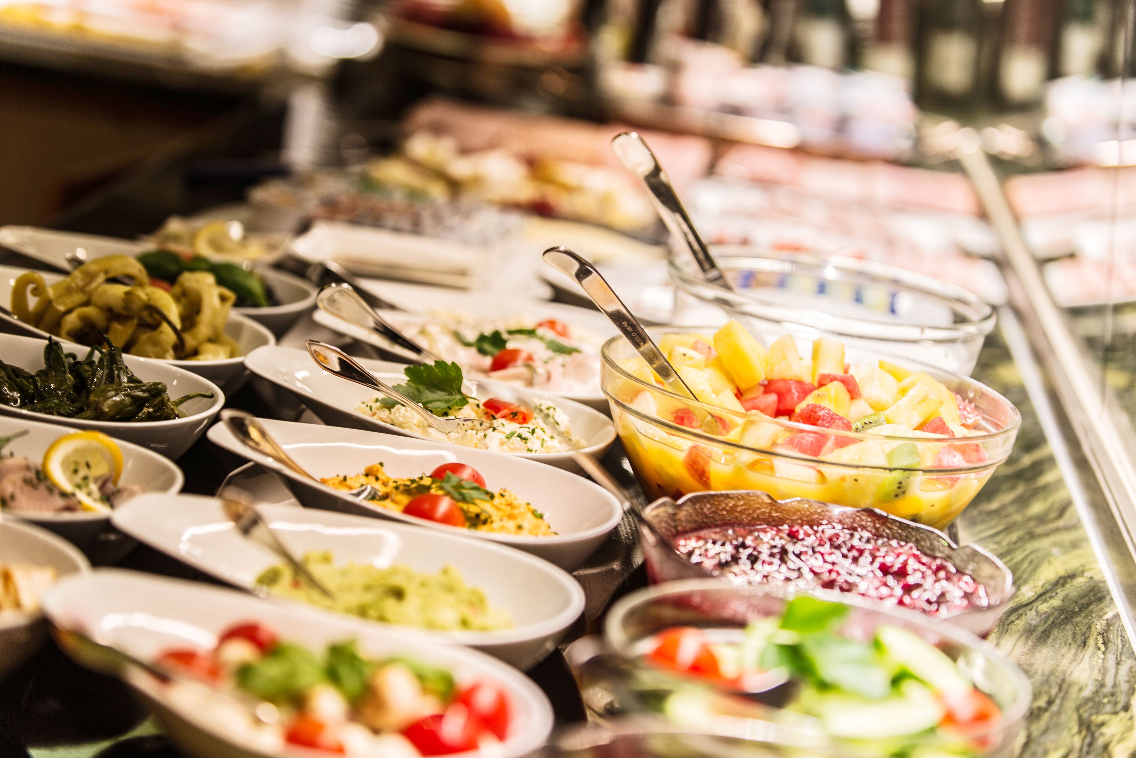 Een buffet met diverse gerechten, waaronder salades, fruit en granen.