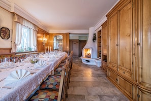 A long dining table set for a meal, flanked by wooden cabinets and a fireplace.