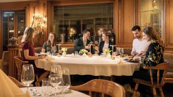 A dining area with a round table, wooden chairs, and a chandelier.