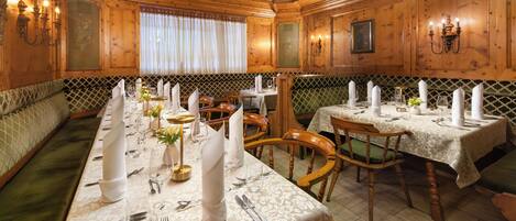 A dining area with wooden paneling, a long table set for a meal, and a bench along the wall.