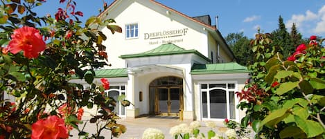 Un hotel con fachada blanca, techo verde y un letrero que dice "DREIFLÜSSEHOF Hotel - Restaurant".