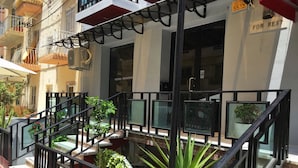 A hotel with a glass-walled atrium, outdoor seating area, and a sign indicating CCTV surveillance. - For Rest Aparthotel (St. Paul's Bay)