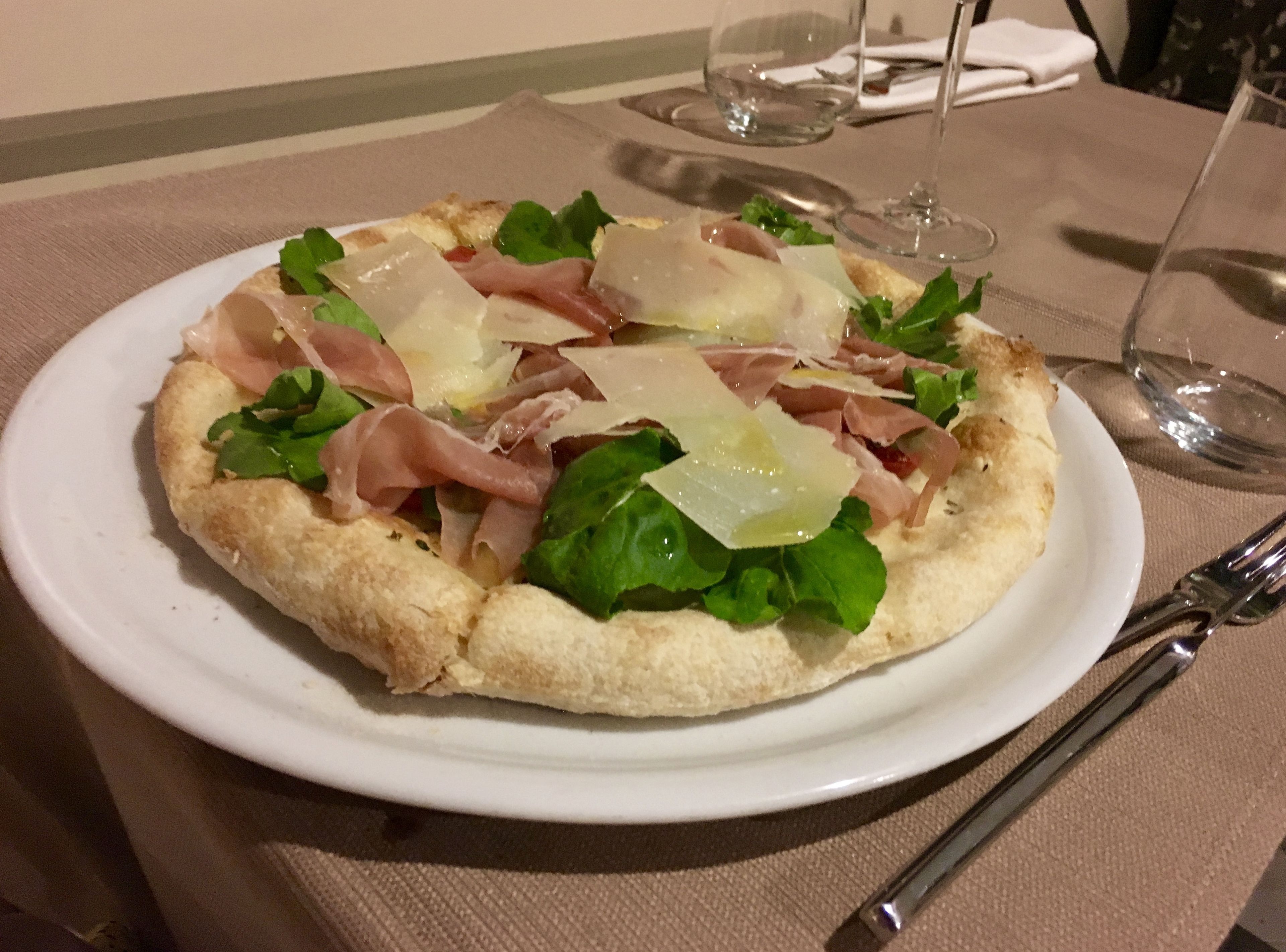 A pizza on a white plate with a tablecloth.