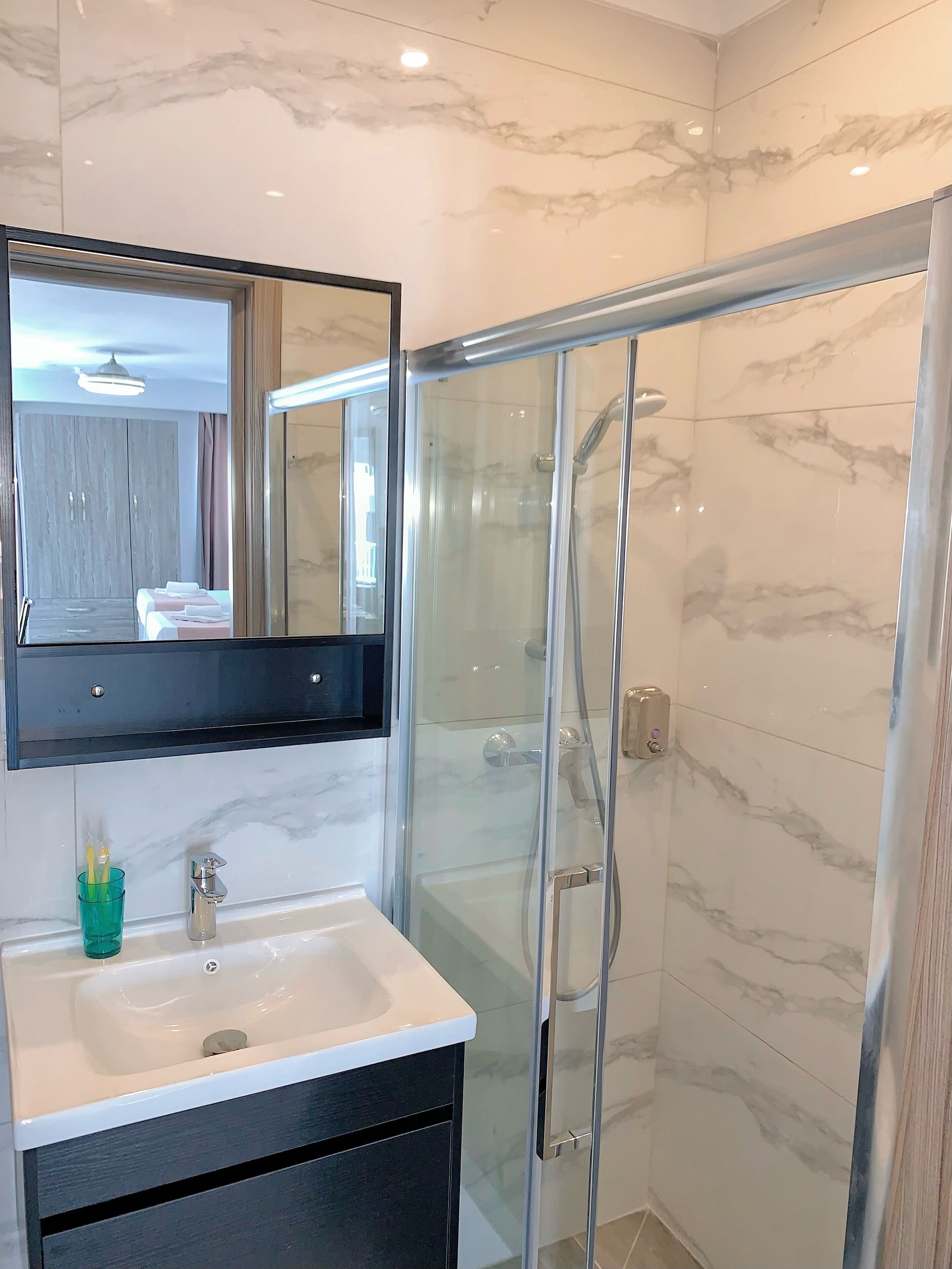 Un bagno moderno con doccia vetrata, un ampio specchio e un lavandino bianco.