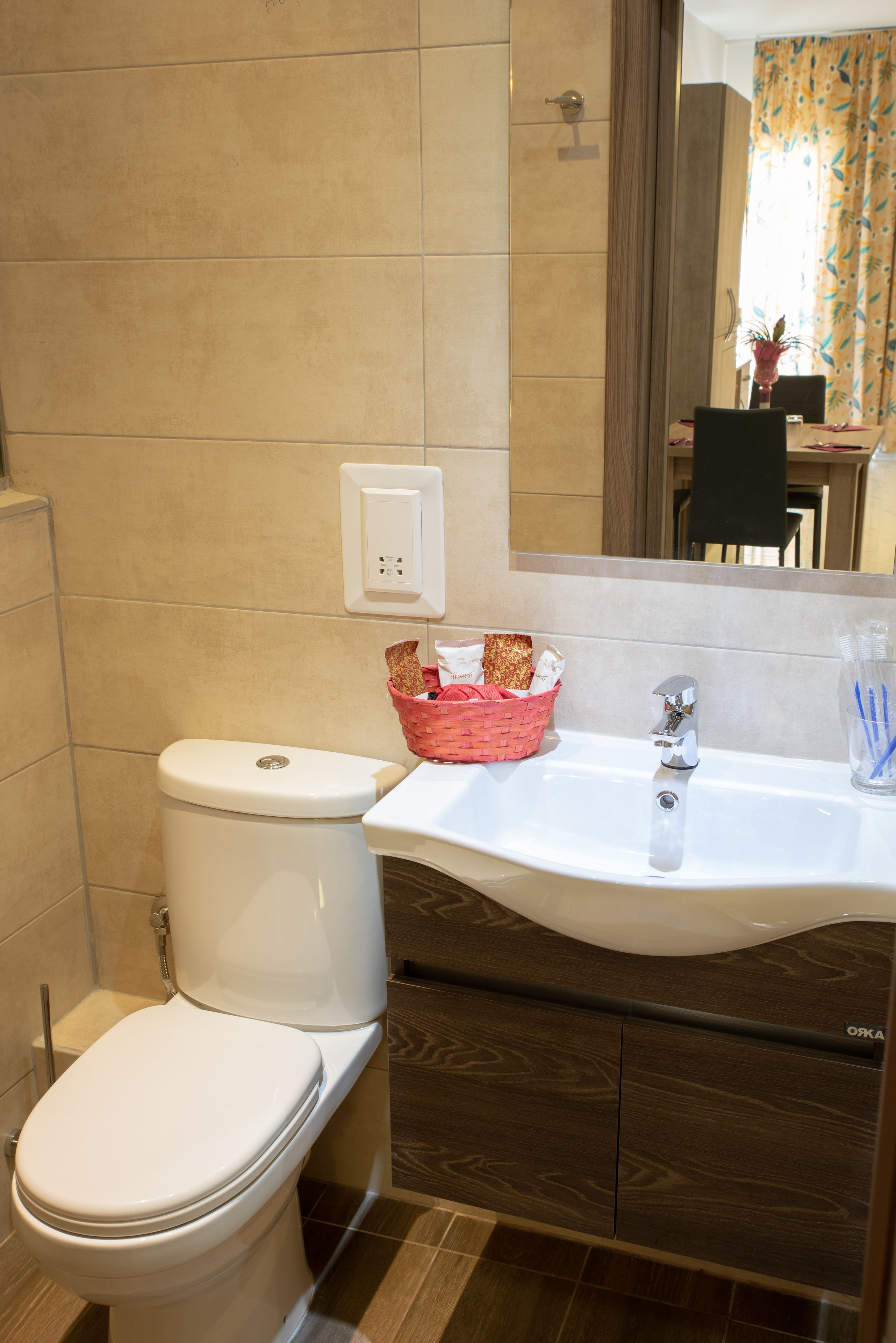 A bathroom with a white toilet, a sink with a mirror above it, and a wooden cabinet below.