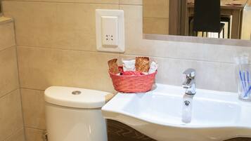 A bathroom with a white toilet, a sink with a mirror above it, and a wooden cabinet below.