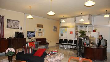 A hotel lobby with a reception desk, seating area, and a television.
