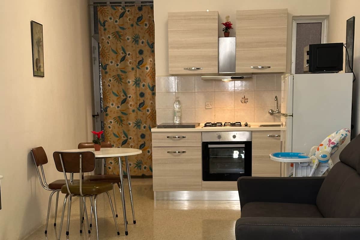 Uma cozinha compacta com área de jantar, um sofá e uma televisão.