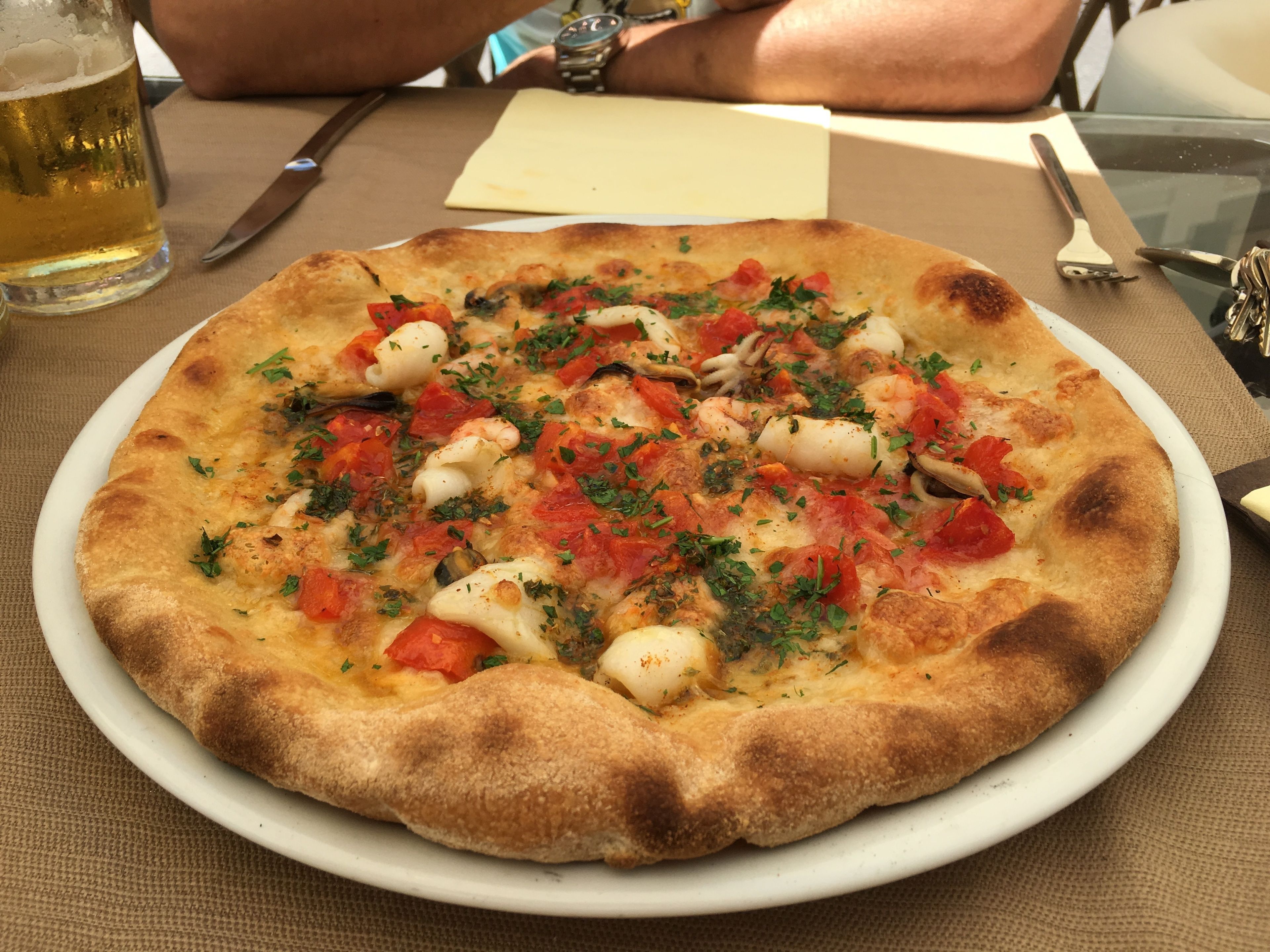 Eine Pizza mit verschiedenen Belägen auf einem weißen Teller.