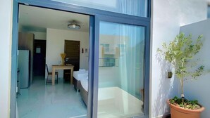 A modern apartment with a sliding glass door leading to a balcony, a small table, and a potted plant. - For Rest Aparthotel (St. Paul's Bay)