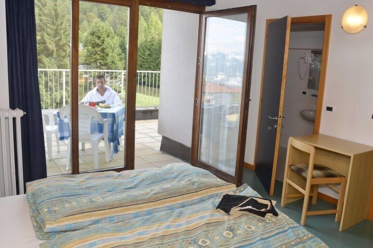 A bedroom with a bed, a wooden desk, and a bathroom door.