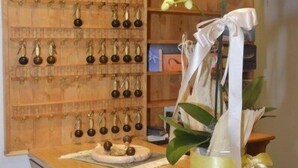 A wooden reception desk with a vase of white orchids and a display of earrings. - Martinella (Folgaria)