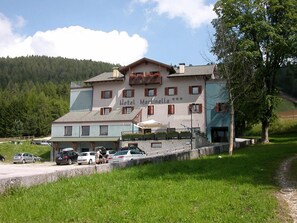 A hotel with a name sign, multiple windows, and a parking area. - Martinella (Folgaria)