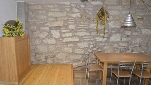 A dining area with a stone wall, a wooden table, and metal chairs. - Martinella (Folgaria)