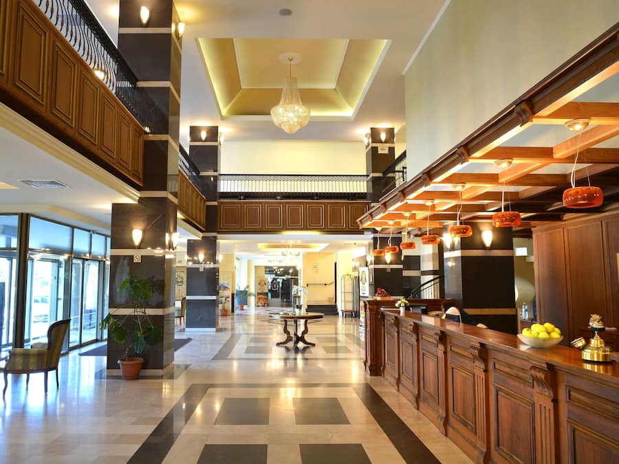 Eine großzügige Lobby mit Schachbrettmuster-Bodenbelag, einem Holzbüro und einer Chandelüster.