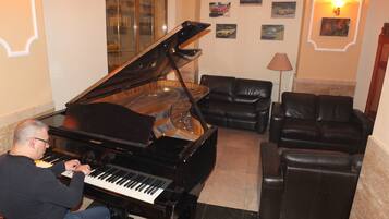 A grand piano in a well-lit room with a sofa and a lamp.