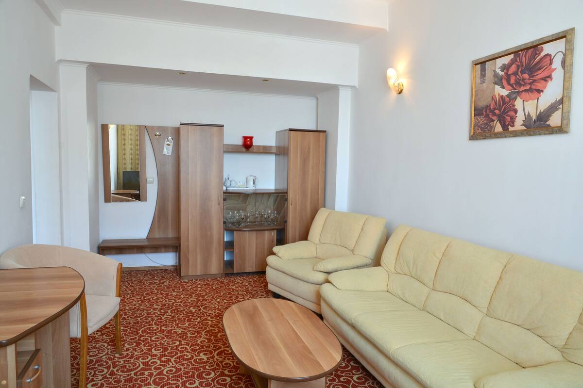 Una sala de estar con un sofá color beige, una mesa de centro de madera y una alfombra estampada.