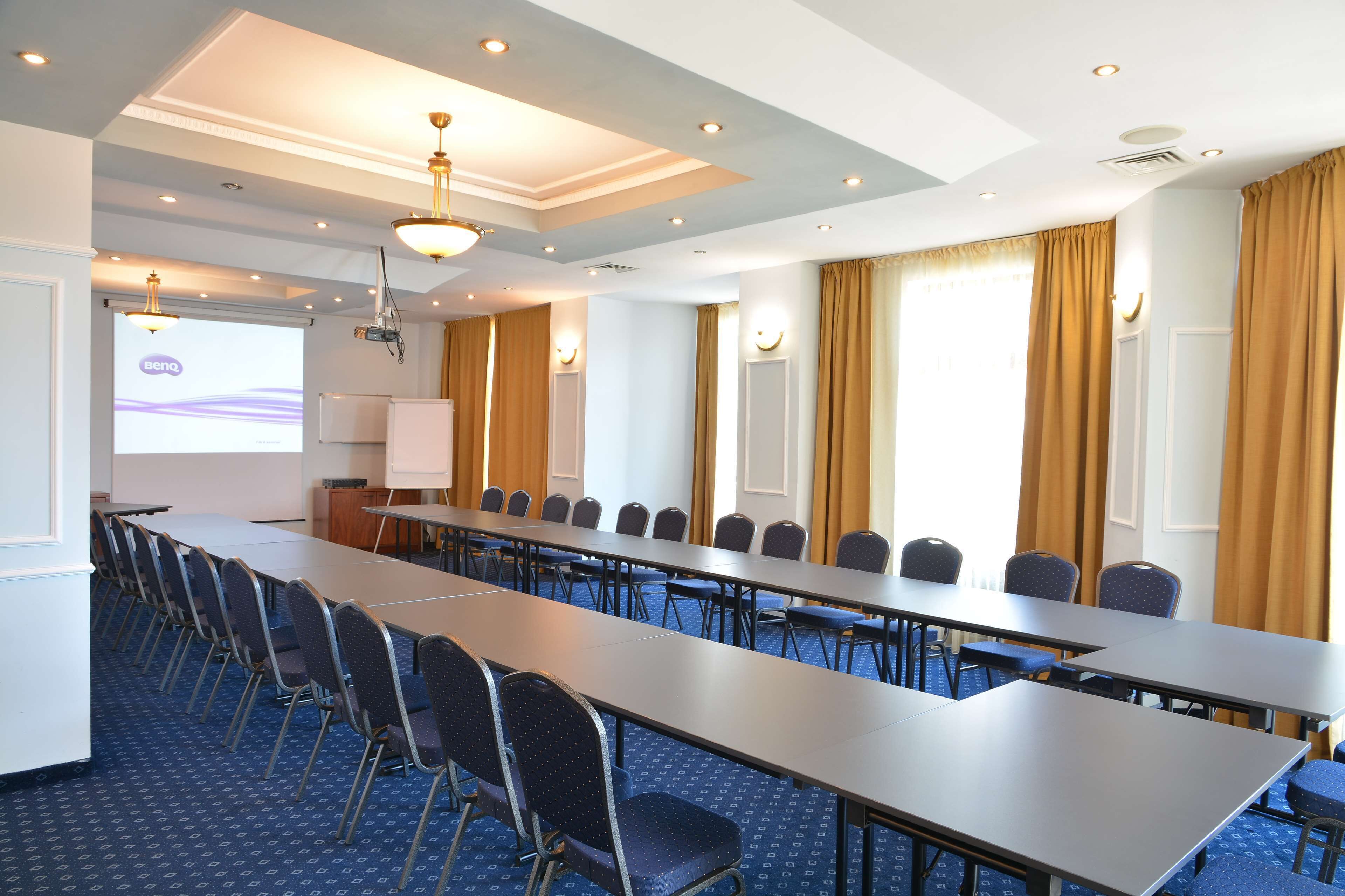 A conference room with a long table, chairs, and a projector screen.