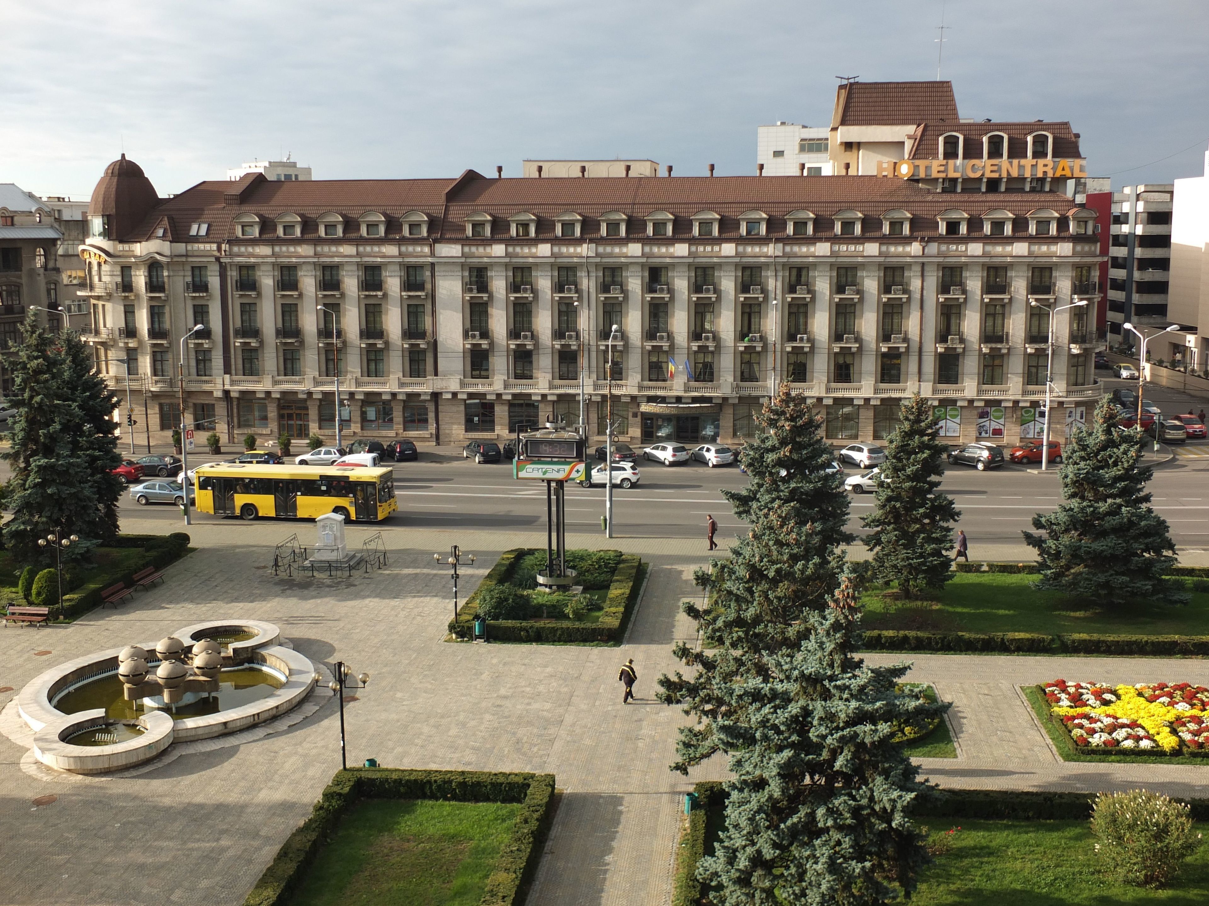 Un edificio grande con un patio central, rodeado de árboles y un jardín de flores.