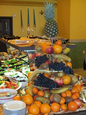 Un bufé con una variedad de frutas y verduras, incluyendo naranjas, manzanas y plátanos.