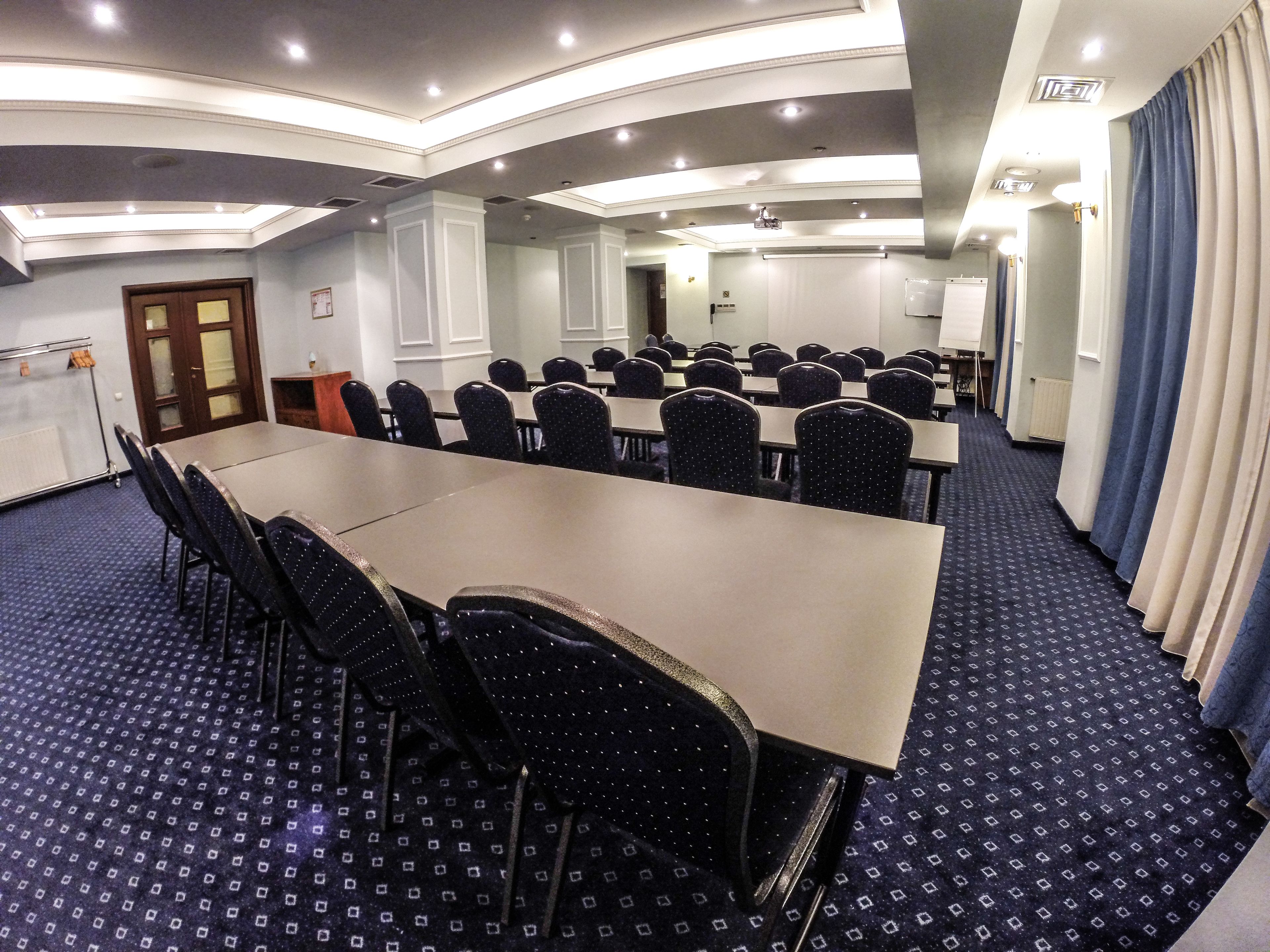 A conference room with a long table, chairs, and a carpeted floor.