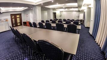 A conference room with a long table, chairs, and a carpeted floor.
