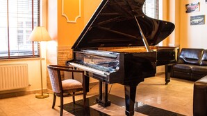 Un piano de cola en una habitación con una silla, una lámpara y un sofá.