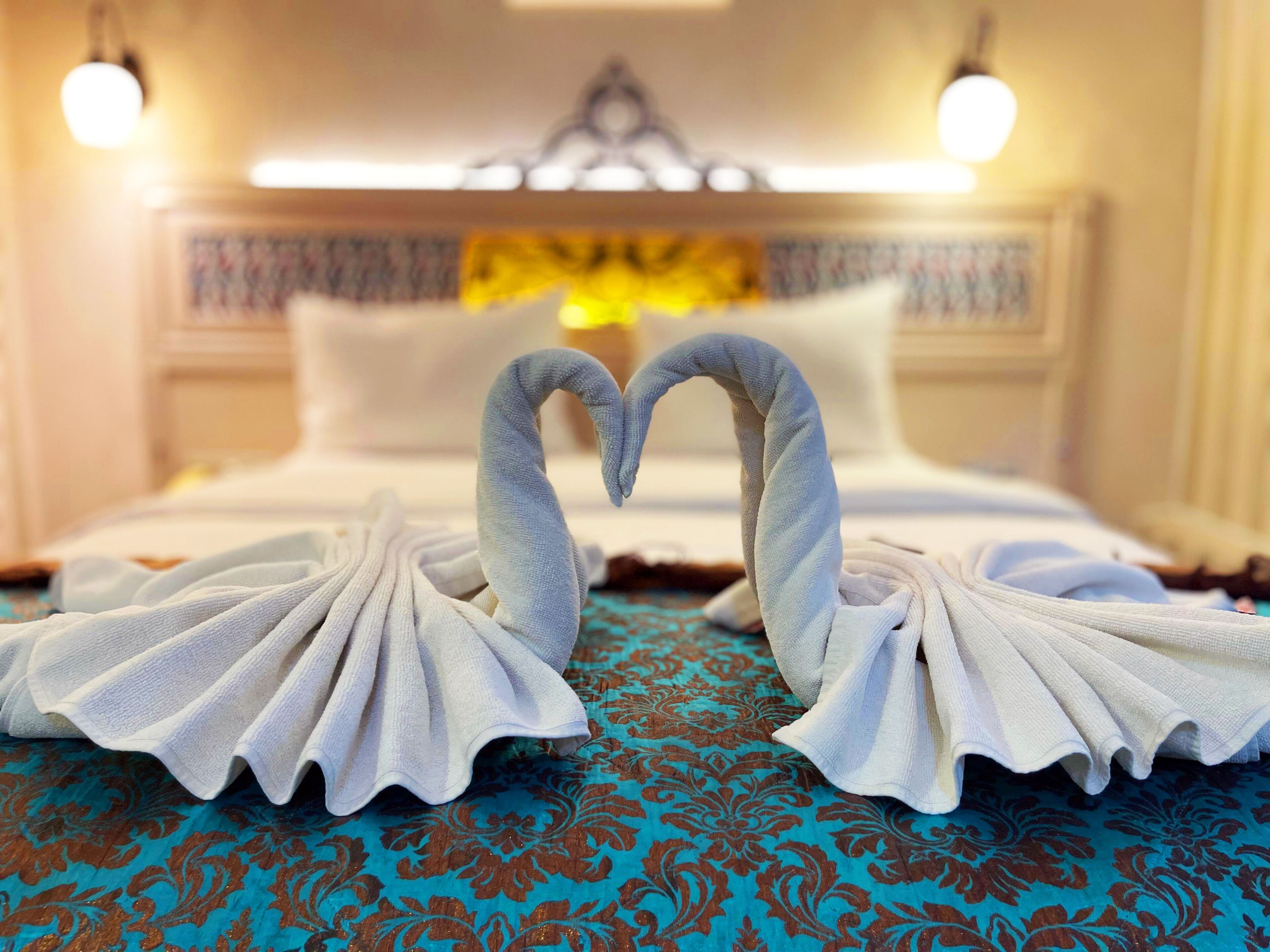 A hotel room with a bed, two wall-mounted lamps, and a decorative wall hanging.