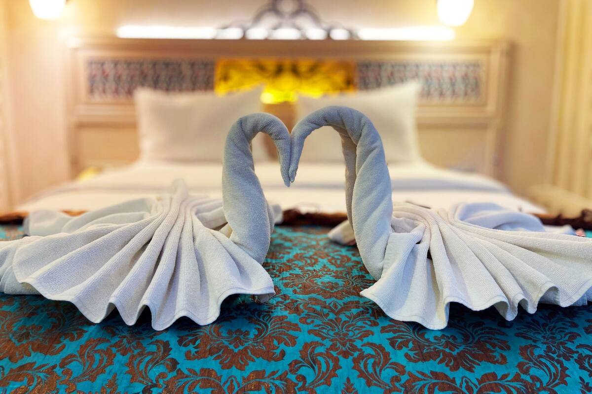 A hotel room with a bed, two wall-mounted lamps, and a decorative wall hanging.
