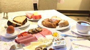 Een ontbijttafel met diverse etenswaren, een kop koffie, en een televisie op de achtergrond.