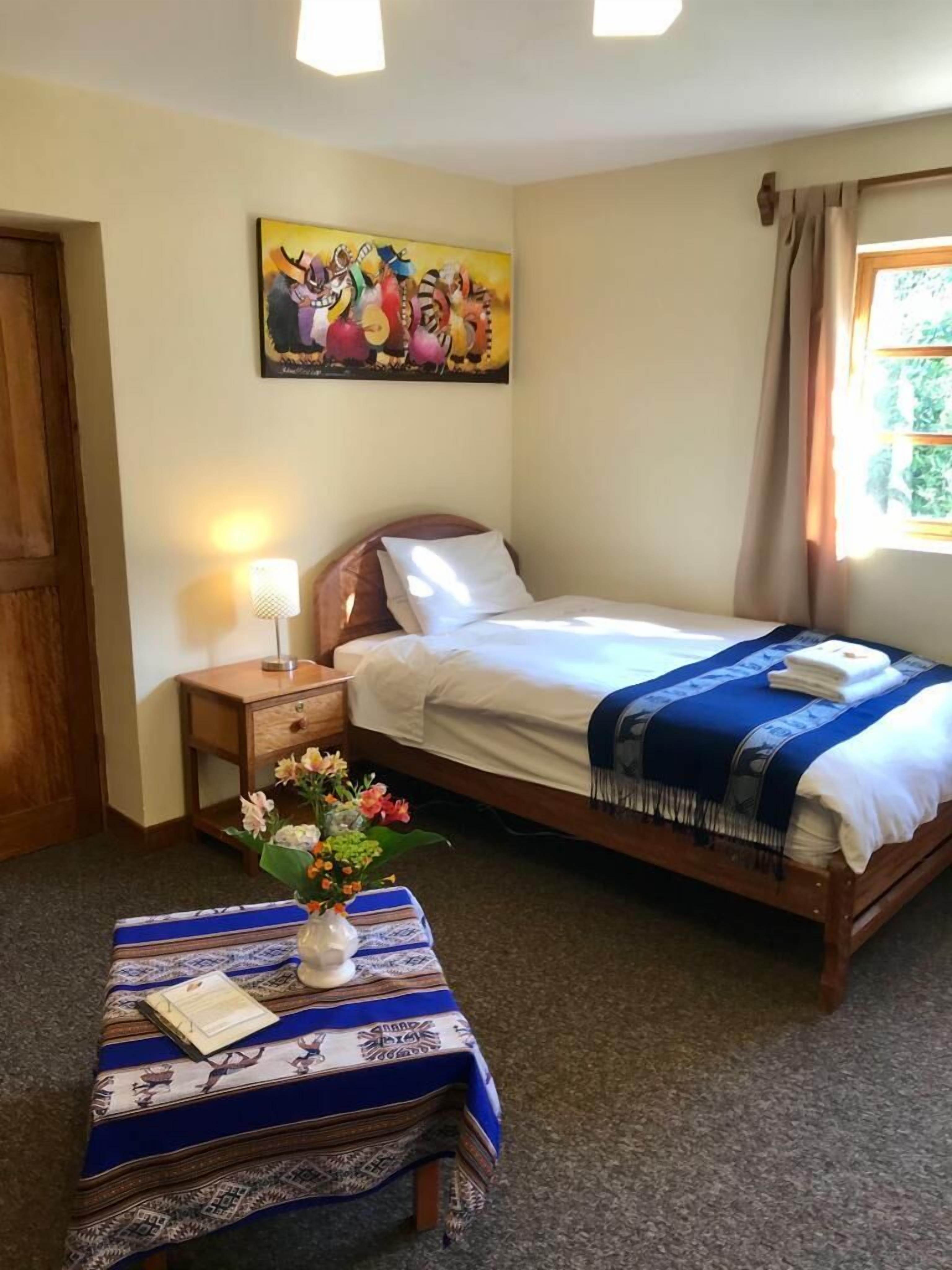 A neatly arranged bedroom with a bed, bedside table, and a small table with a vase of flowers.
