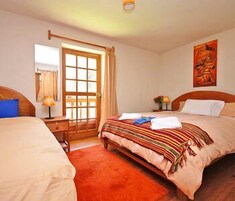 Habitación de hotel con dos camas, un cabecero de madera, una ventana con cortinas, un cuadro en la pared y una alfombra roja.