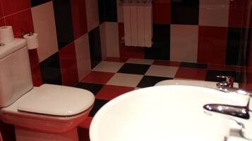 A bathroom with a red and black checkered floor, a white toilet, and a large white sink.