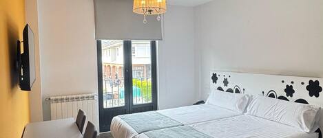 A hotel room with a bed, a desk, a chair, a chandelier, and a view of the outside.