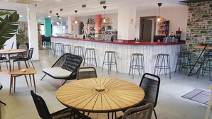 A modern bar area with a counter, stools, and a round wooden table with chairs. - Calas de Liencres (Pielagos)