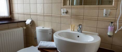 Un baño con un inodoro blanco, un lavabo blanco y un espejo sobre el lavabo.