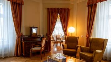 Una sala de estar acogedora con un piano, asientos cómodos y una mesa de centro de vidrio.
