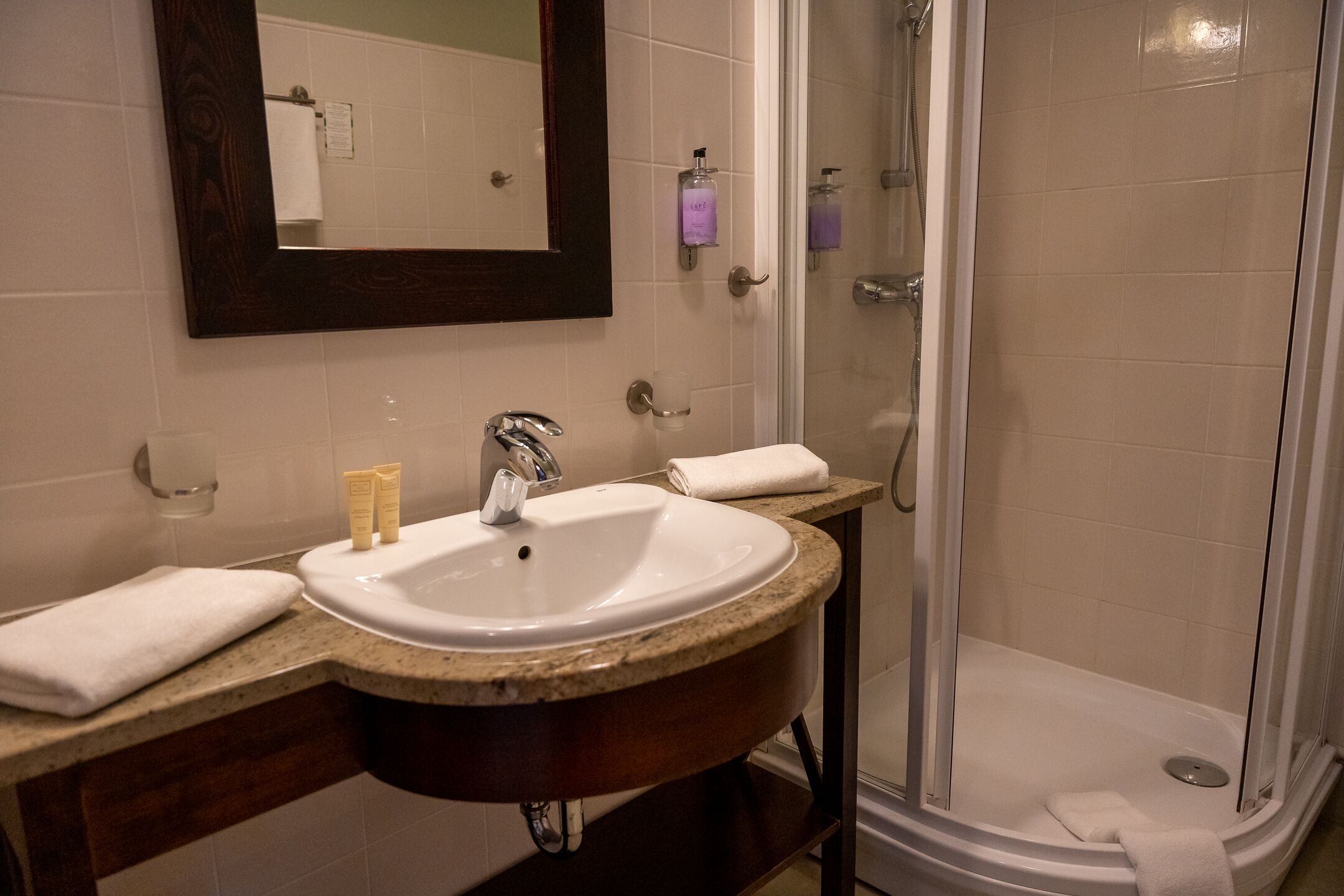 A bathroom with a sink, mirror, and shower.