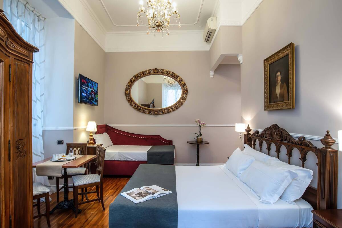 A hotel room with a bed, bedside table, lamp, and a mirror.