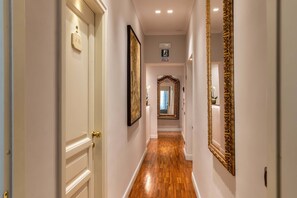 A hallway with wooden flooring, white walls, and a large ornate mirror. -  I TRE MOSCHETTIERI - D' ARTAGNAN Luxury Guest House (Rome)